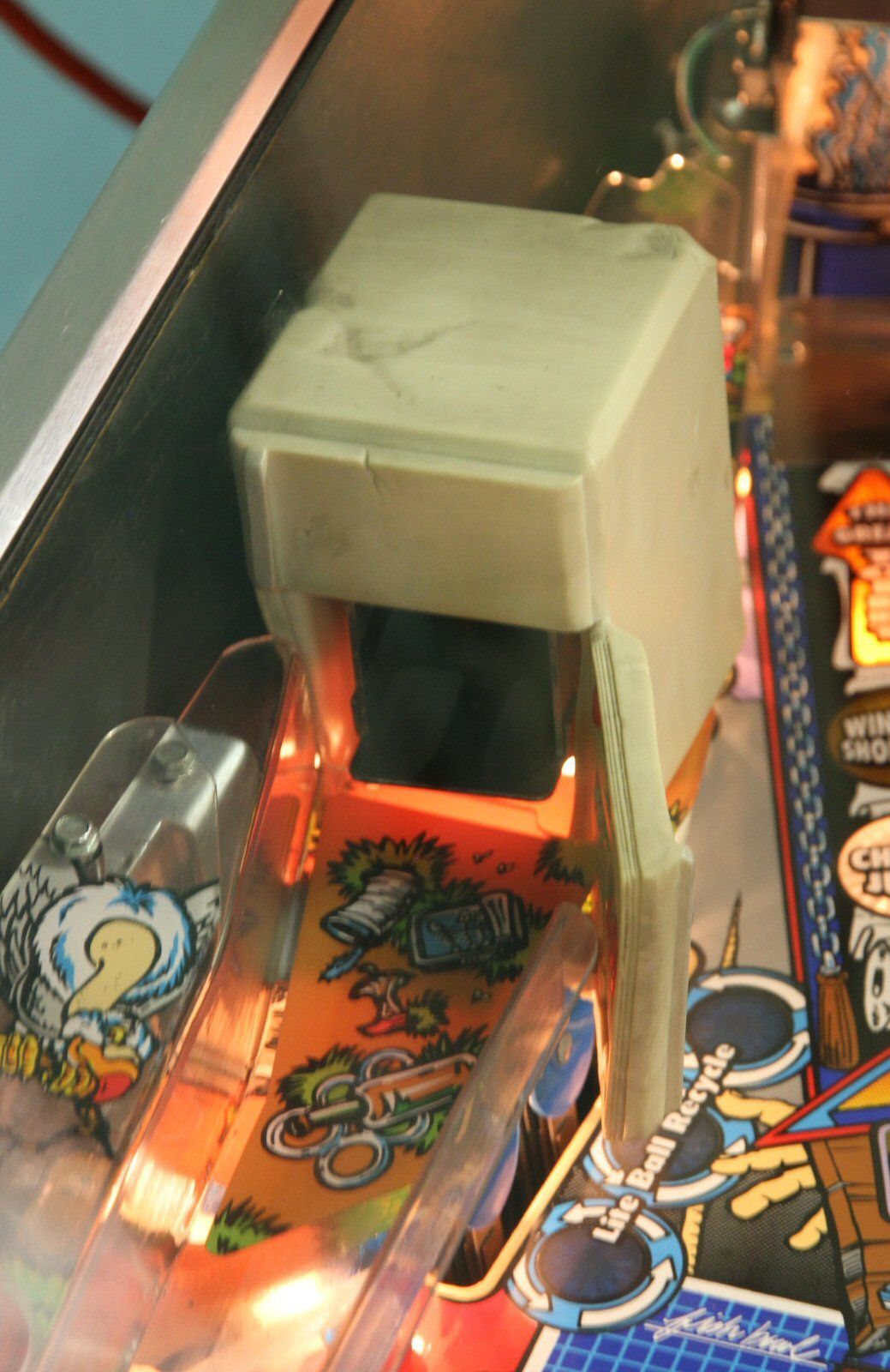 The white refrigerator toy on a real playfield, lit from inside.